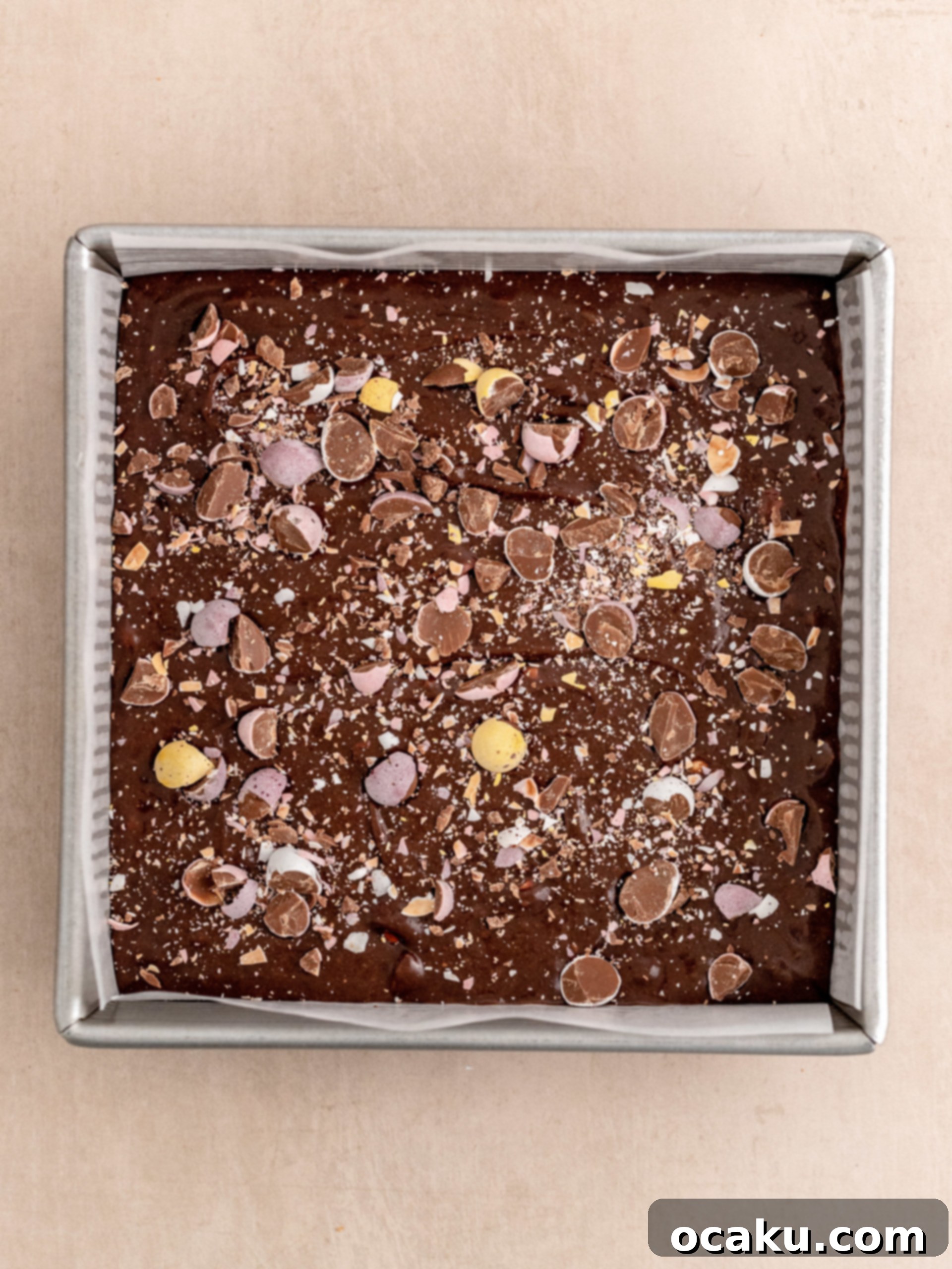 A freshly baked pan of Mini Egg Brownies, cooling on a wire rack, with vibrant mini eggs on top.