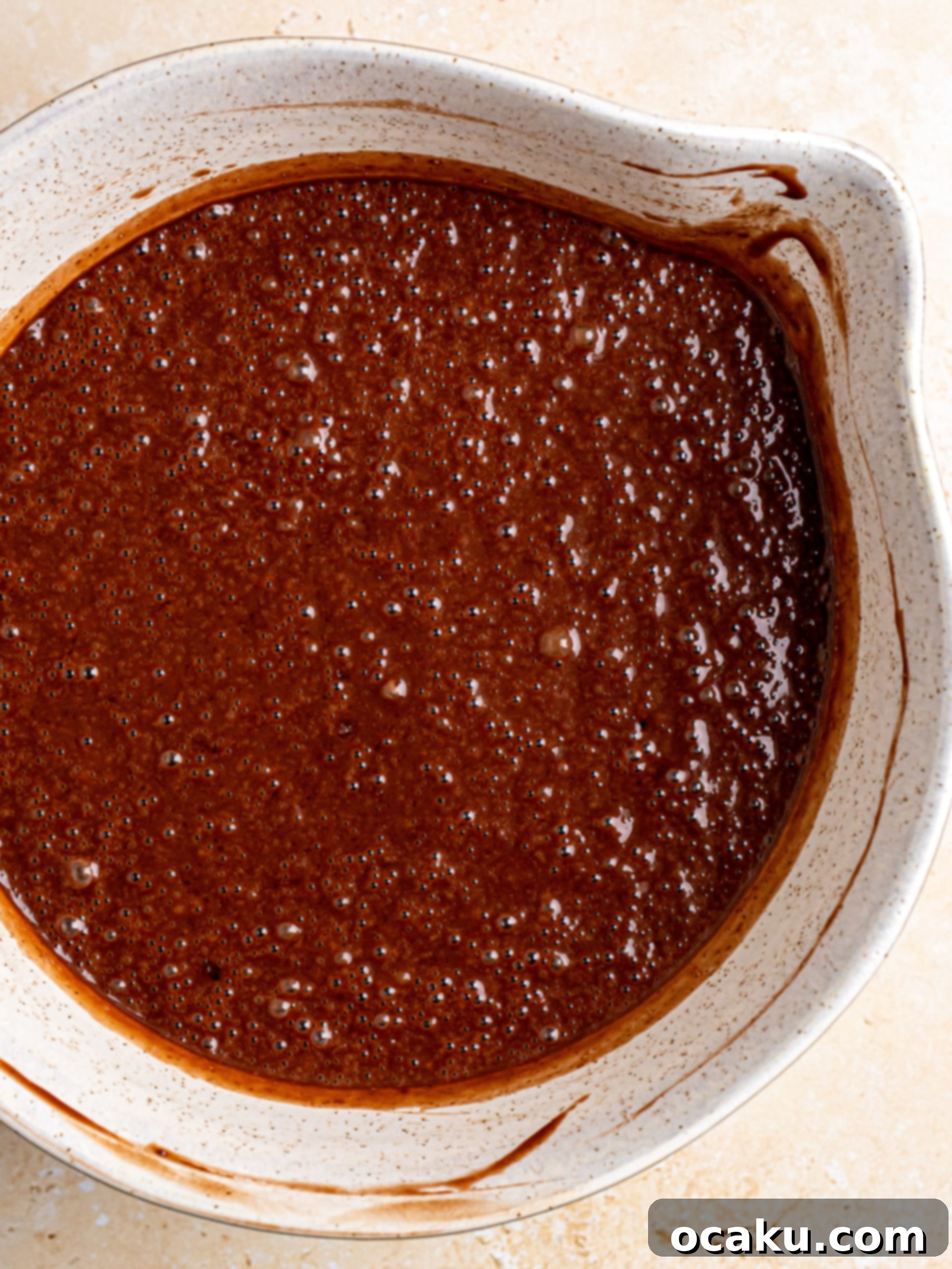 Stacking chocolate cake layers with fudge frosting in between.