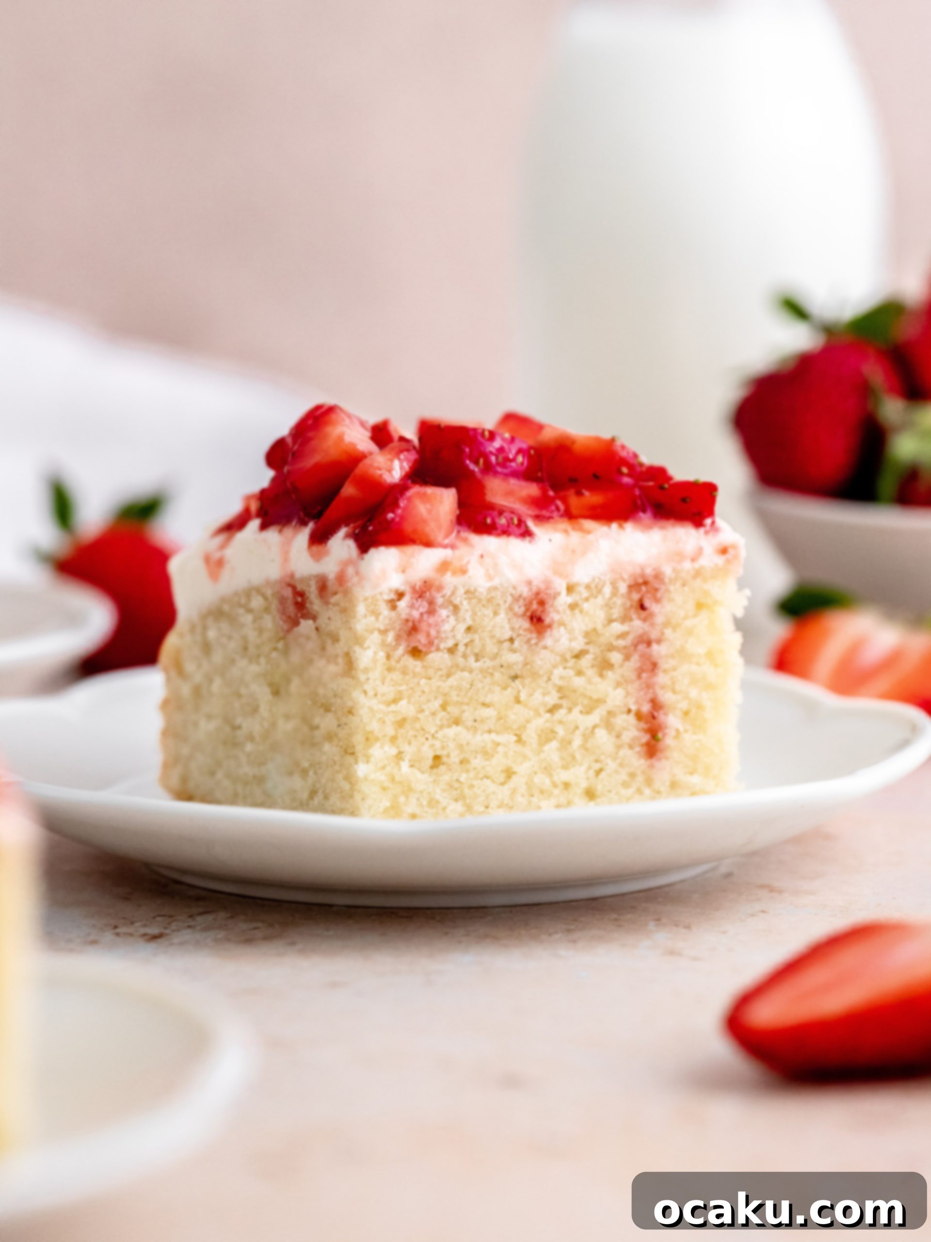 Close-up of a slice of Strawberry Vanilla Cake with fresh strawberries.