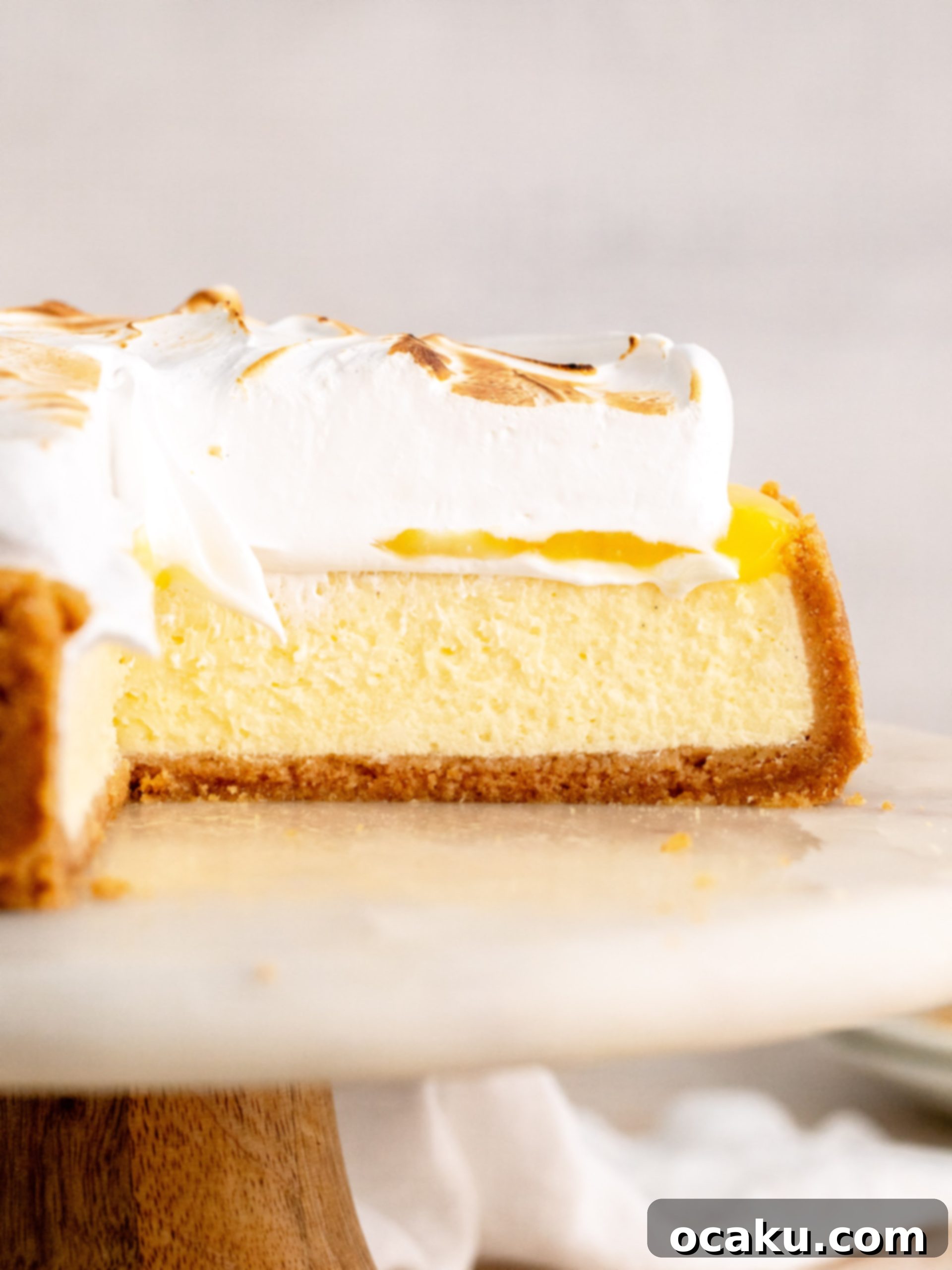 A slice of Lemon Meringue Cheesecake on a white plate, showcasing all layers