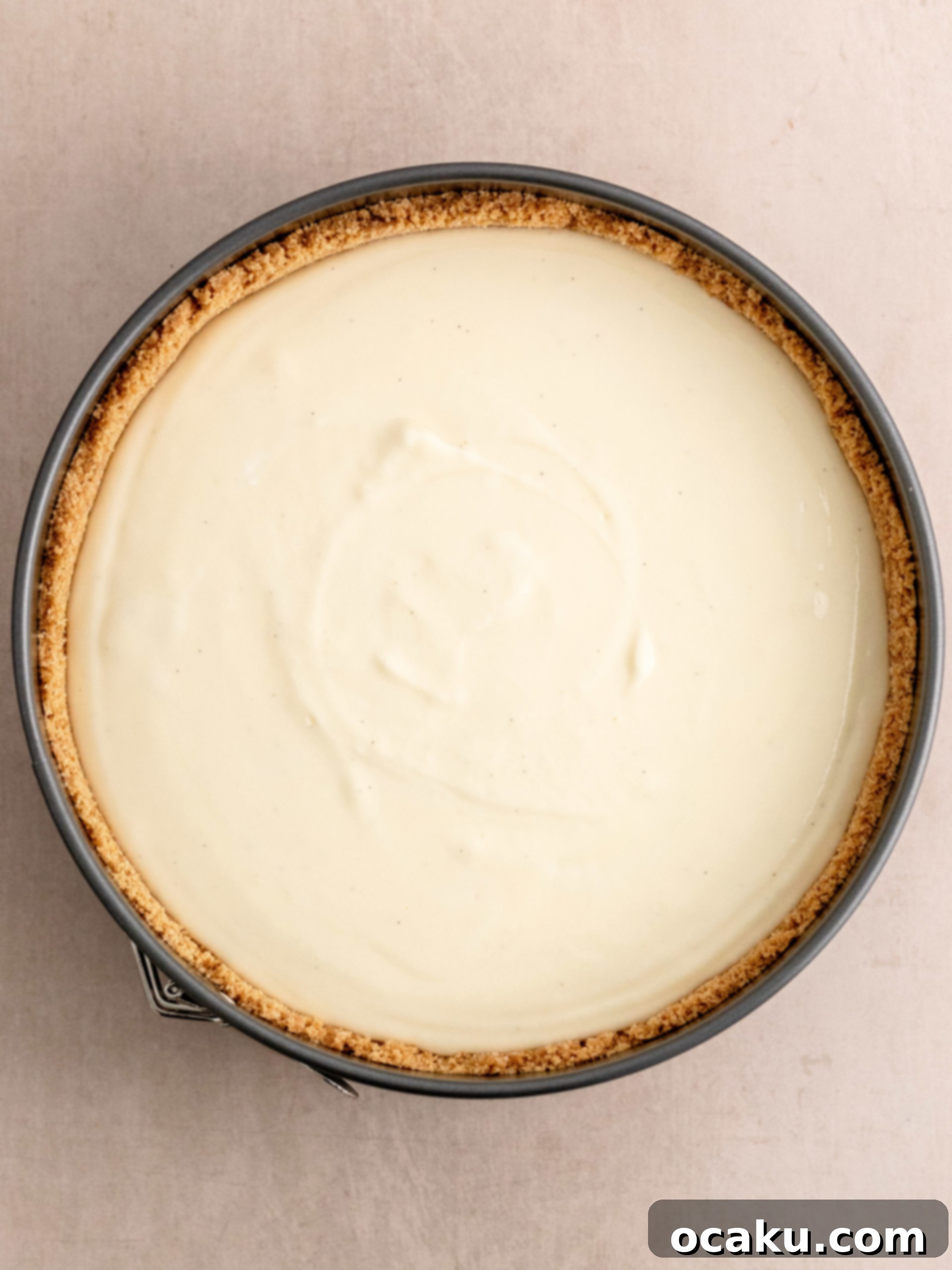 Cookie crust being pressed into a springform pan with a glass