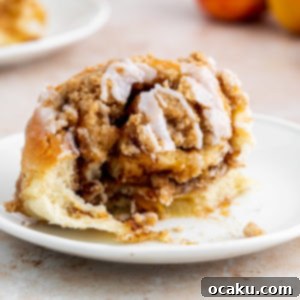 Close-up of freshly baked Peach Cobbler Cinnamon Rolls with glaze and crumble.