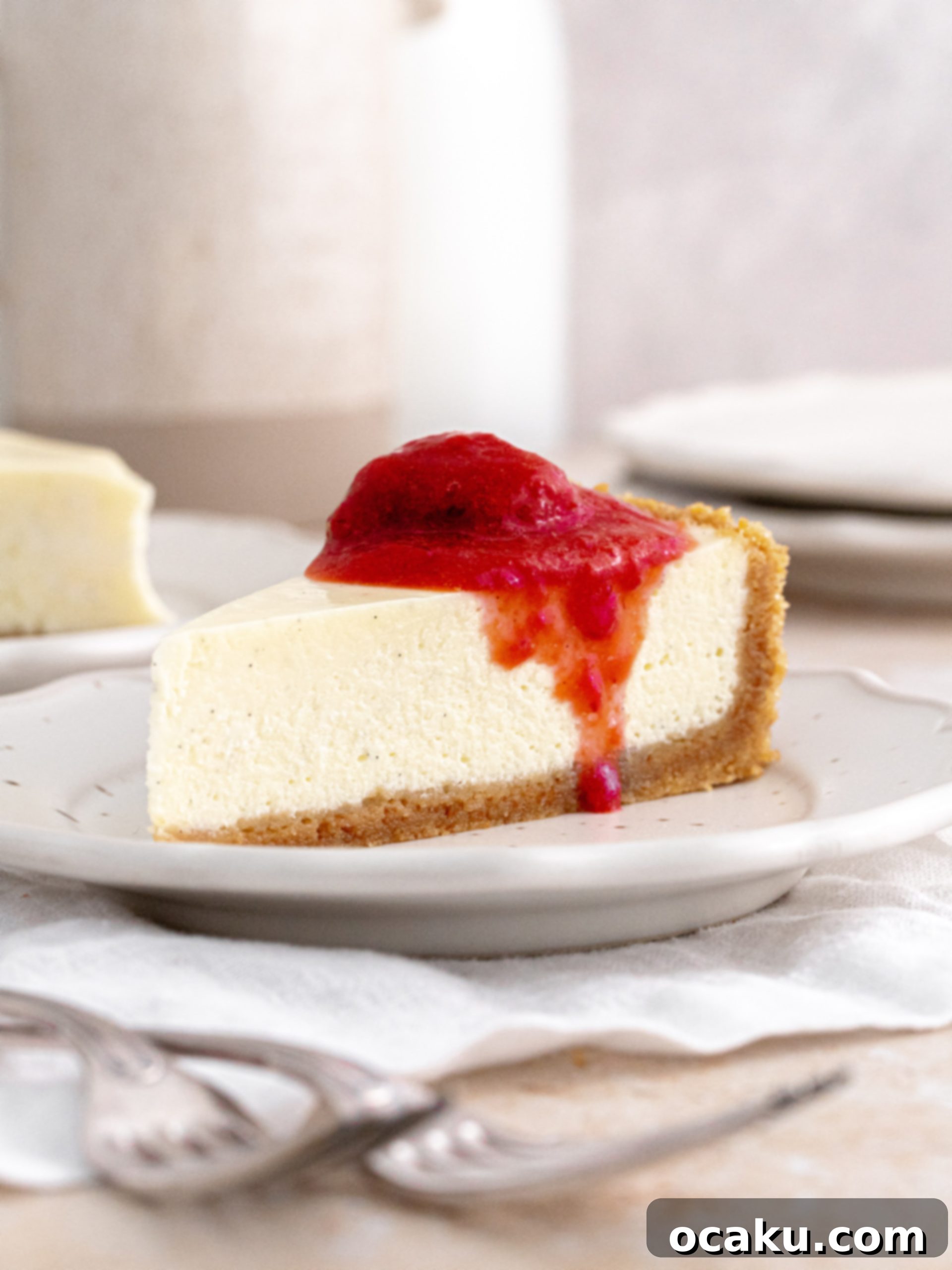 Decadent Vanilla Cheesecake 8 A slice of vanilla cheesecake topped with strawberry compote on a white plate