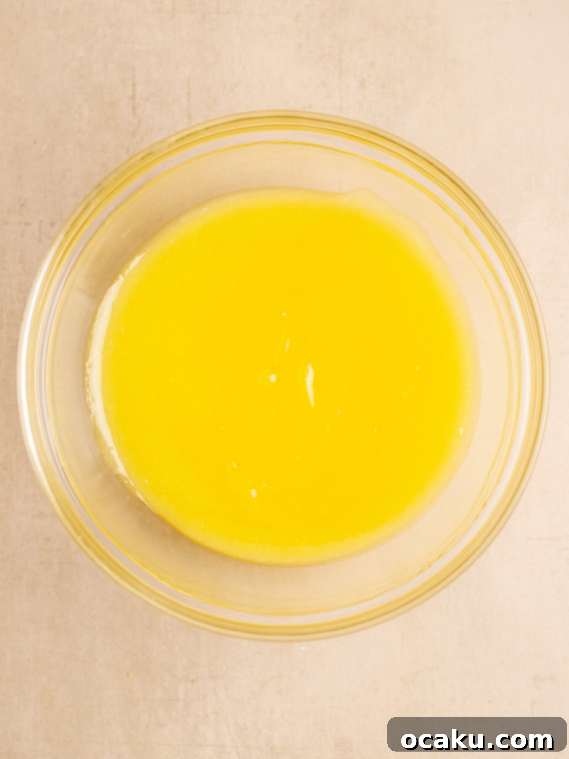 Lemon curd being strained through a sieve into a bowl
