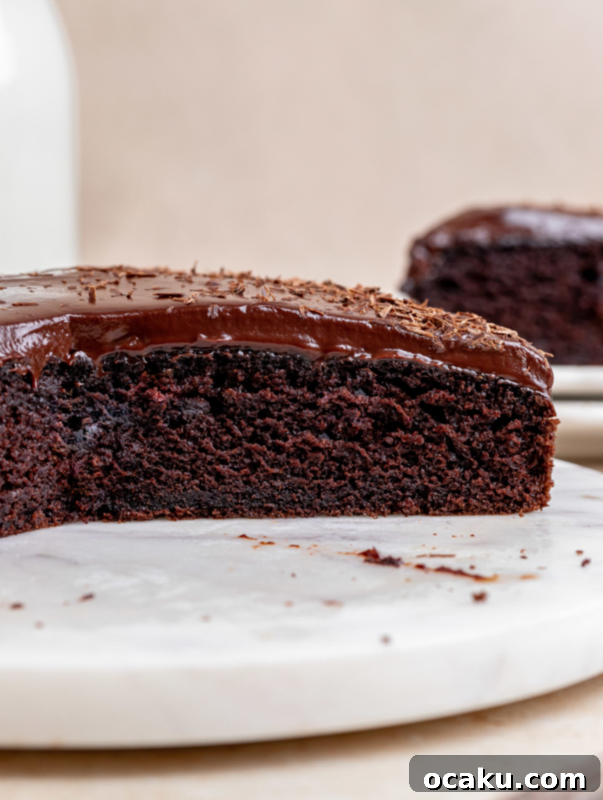 A close-up of a beautifully decorated chocolate ganache cake with chocolate shavings.