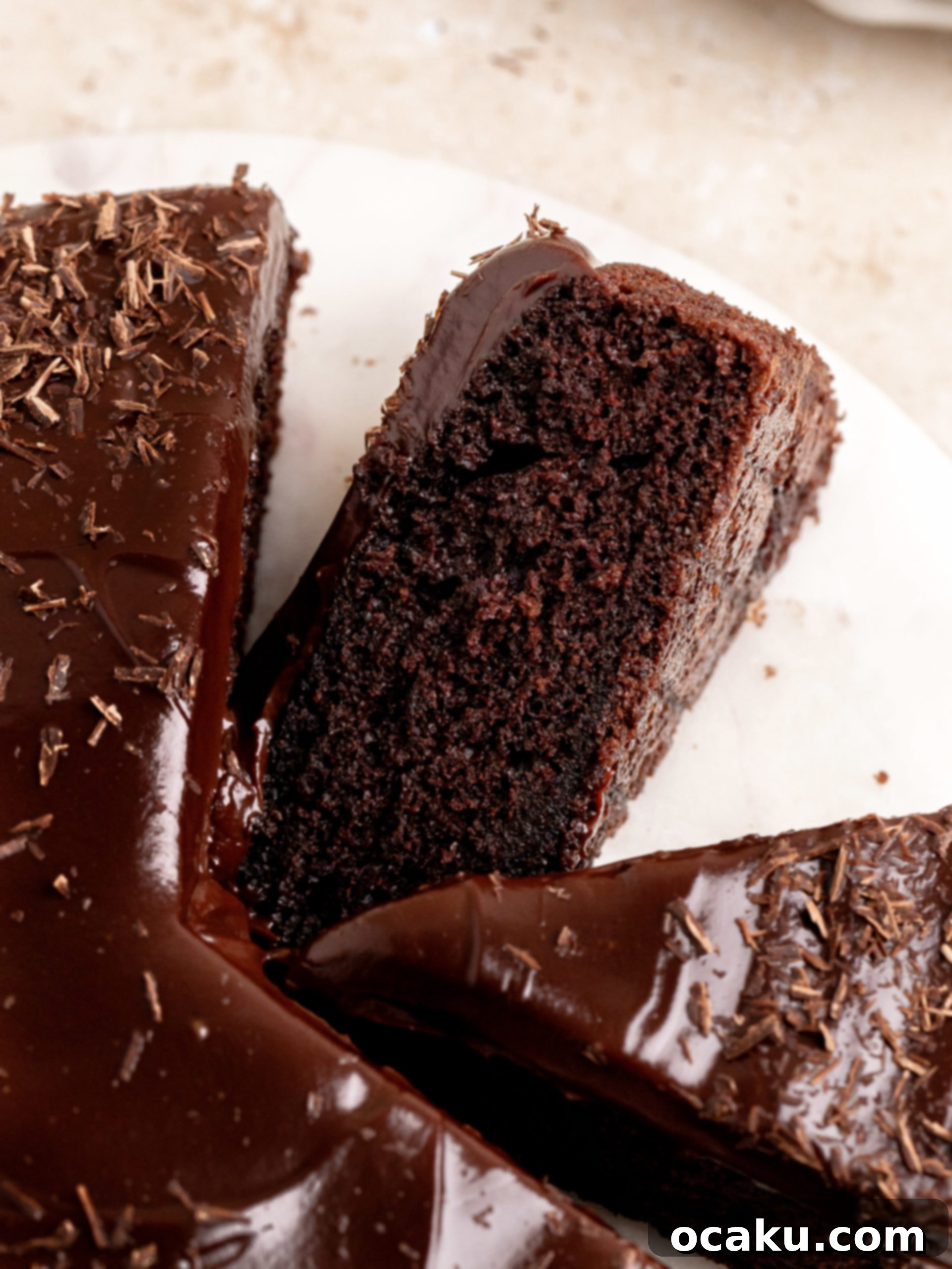 A whole chocolate ganache cake, ready for serving, showing its rich color and smooth topping.