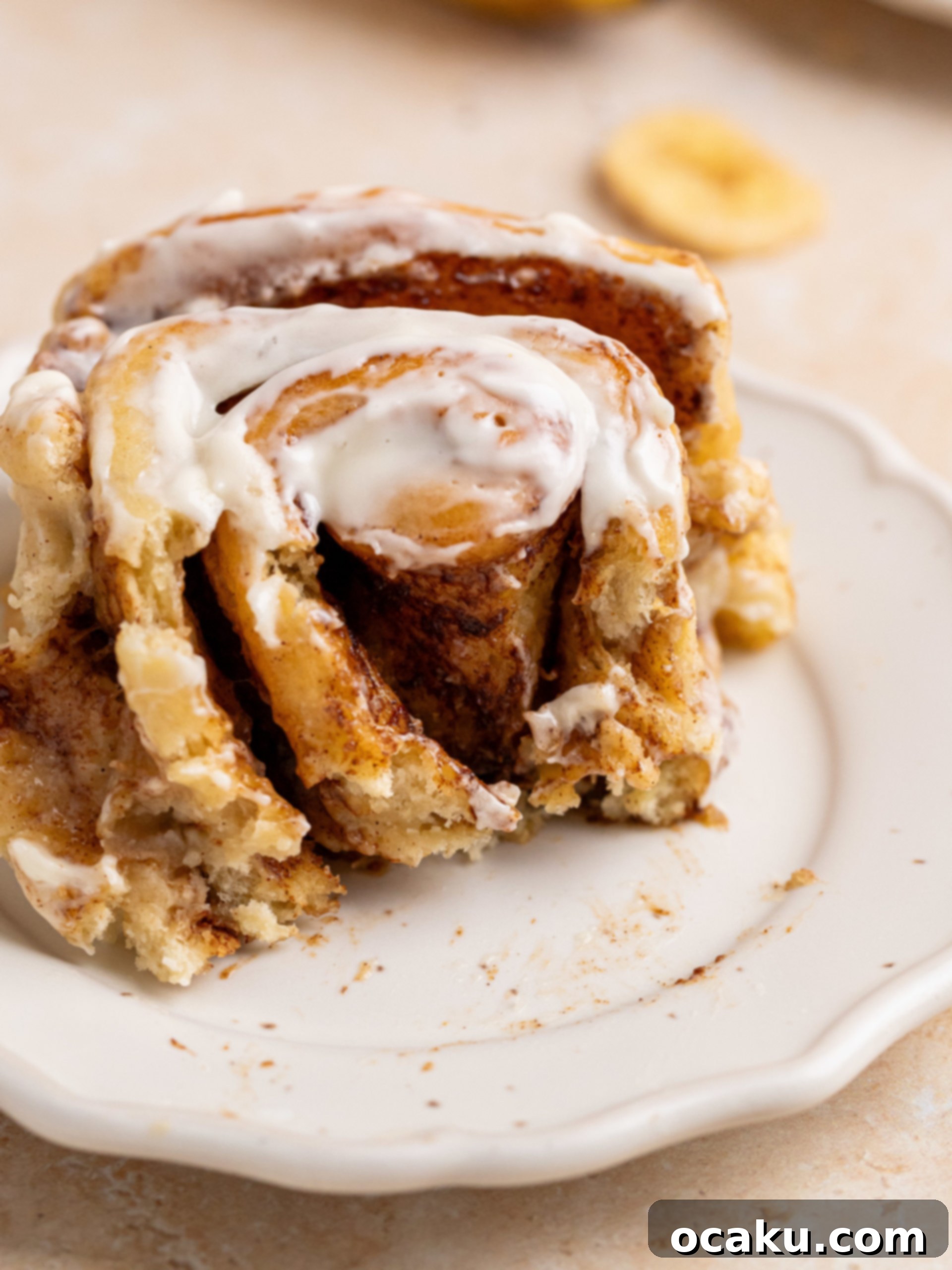 Close-up of a stack of banana cinnamon rolls with creamy frosting.