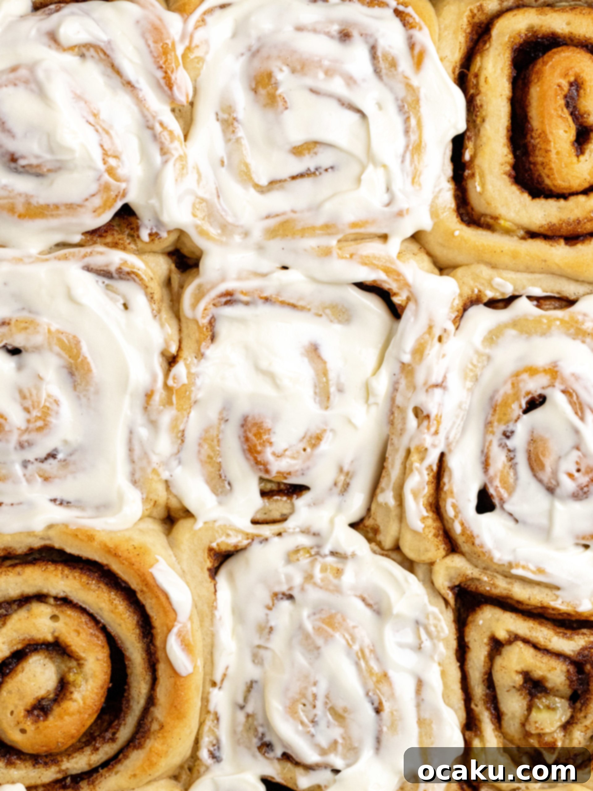 Close-up of baked Banana Cinnamon Rolls with gooey filling and frosting.