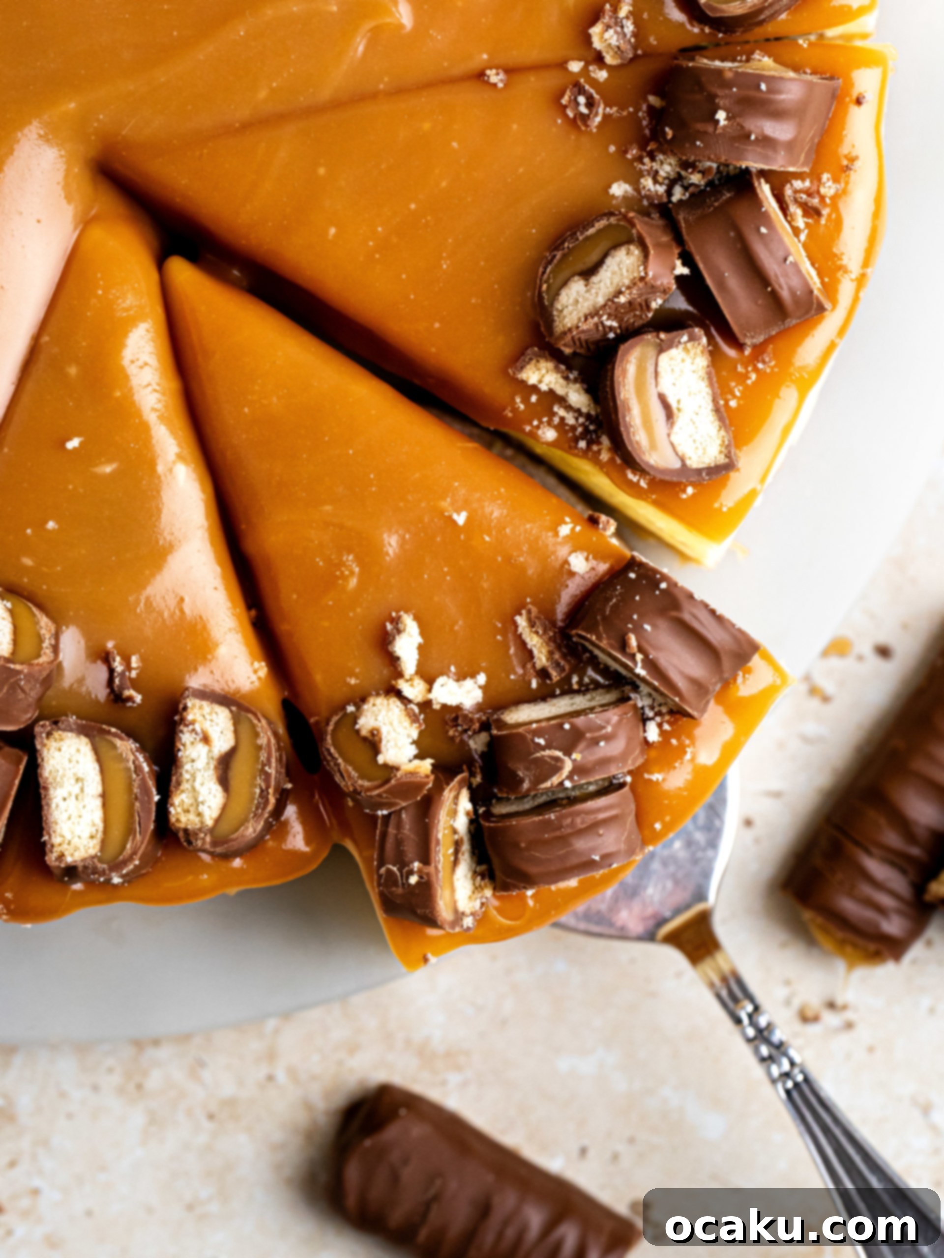 Twix Caramel Cheesecake 2 A slice of Twix Cheesecake on a plate, showing the shortbread crust, creamy filling with Twix pieces, and caramel topping.