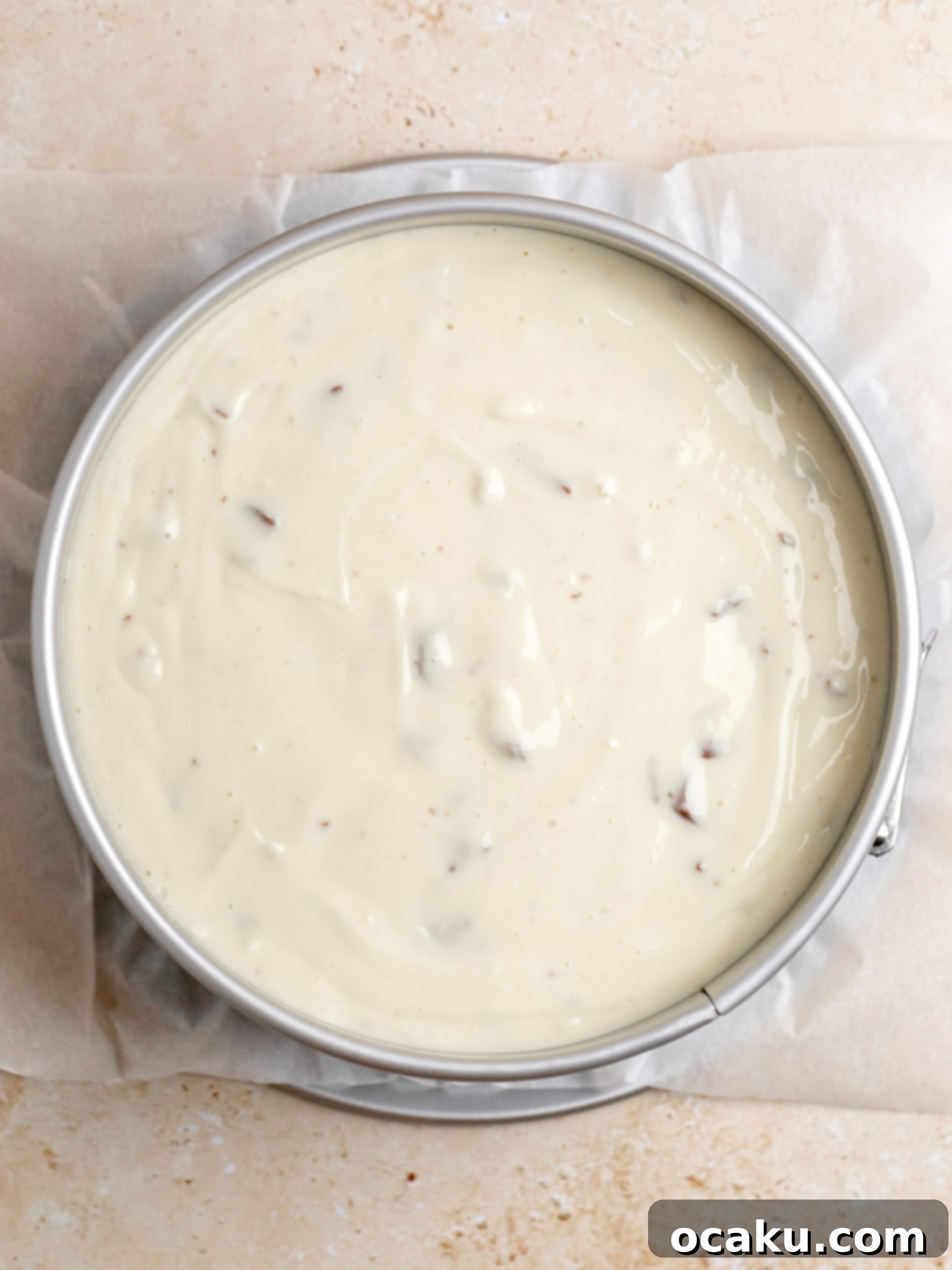 Twix Caramel Cheesecake 9 Step-by-step image showing chopped Twix bars being gently folded into the cheesecake batter.