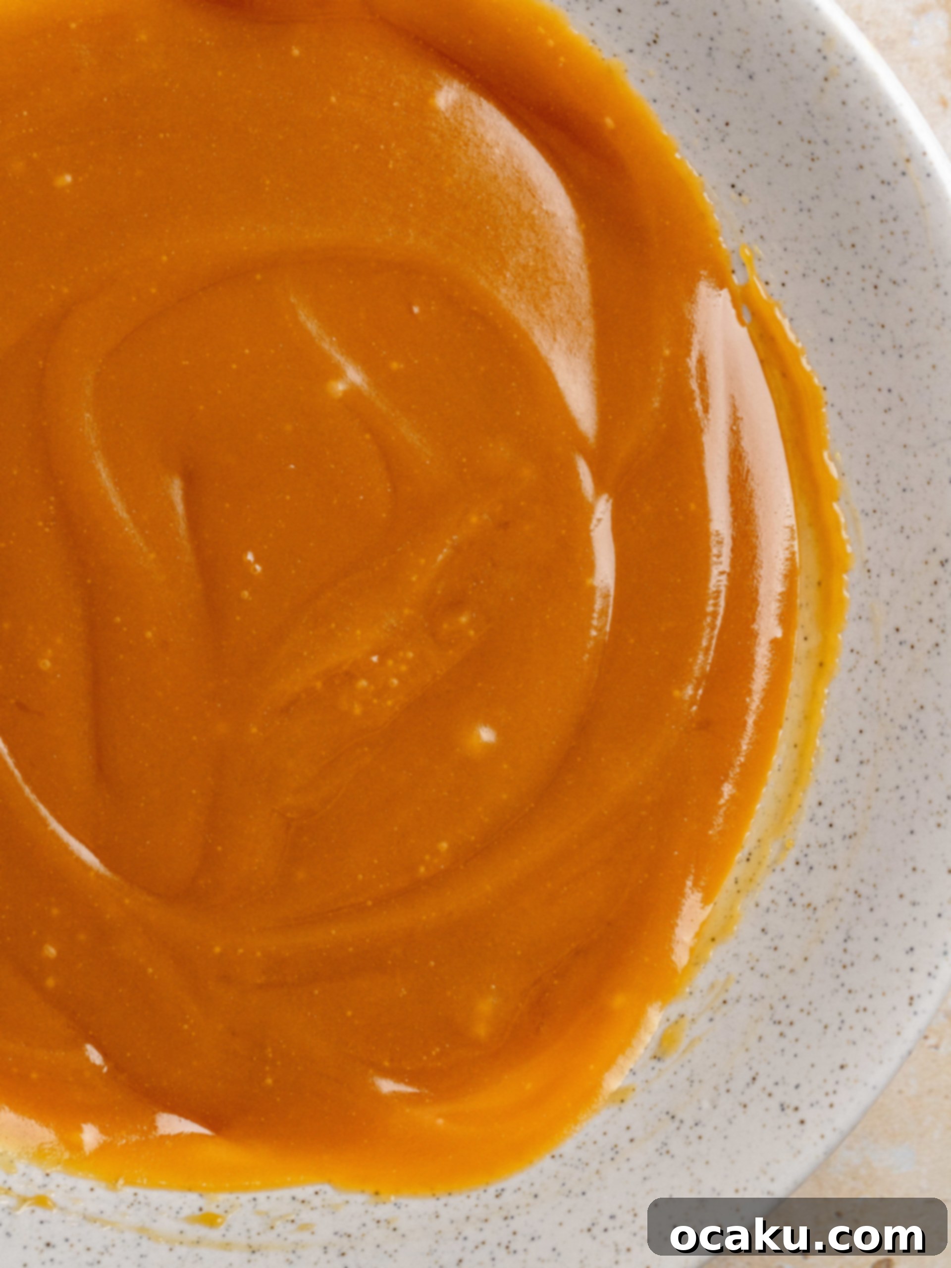 Caramel sauce being poured over warm cinnamon rolls.