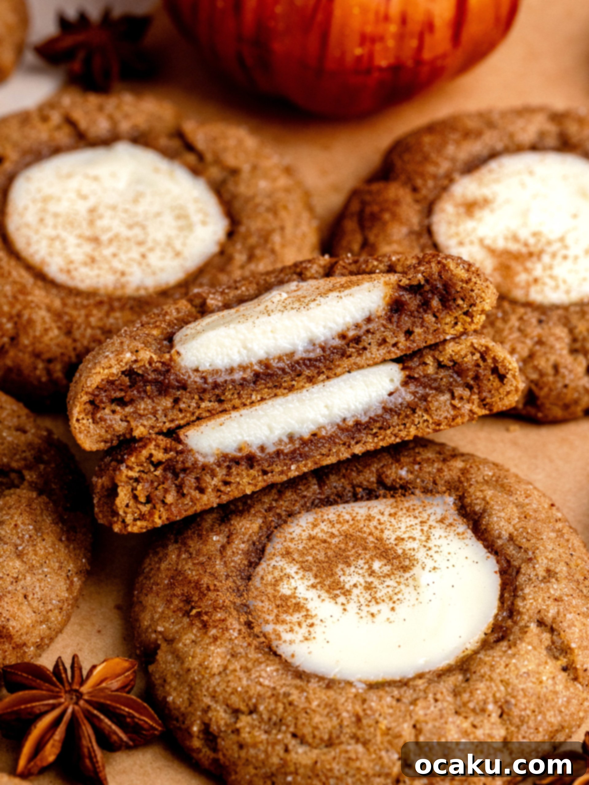 Delicious pumpkin cheesecake cookie broken in half, showing the gooey cheesecake filling inside.