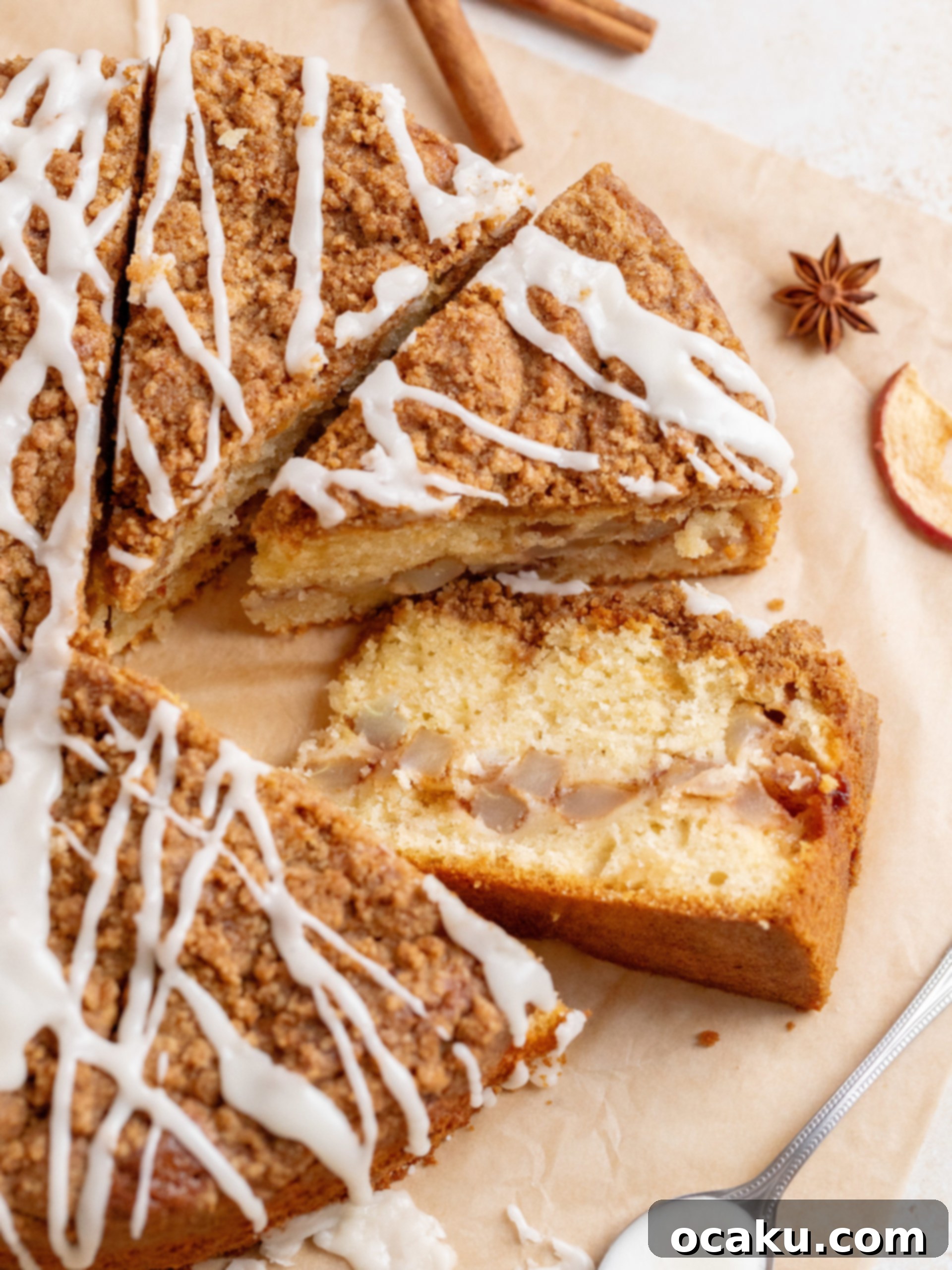 A beautifully baked Apple Crumb Cake with a generous maple glaze, showcased on a wooden board.