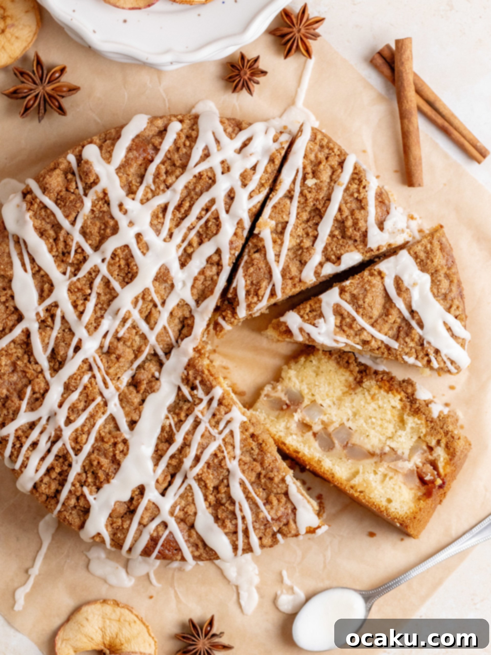 A perfectly baked and glazed Apple Crumb Cake, with a single slice removed and a fork nearby.