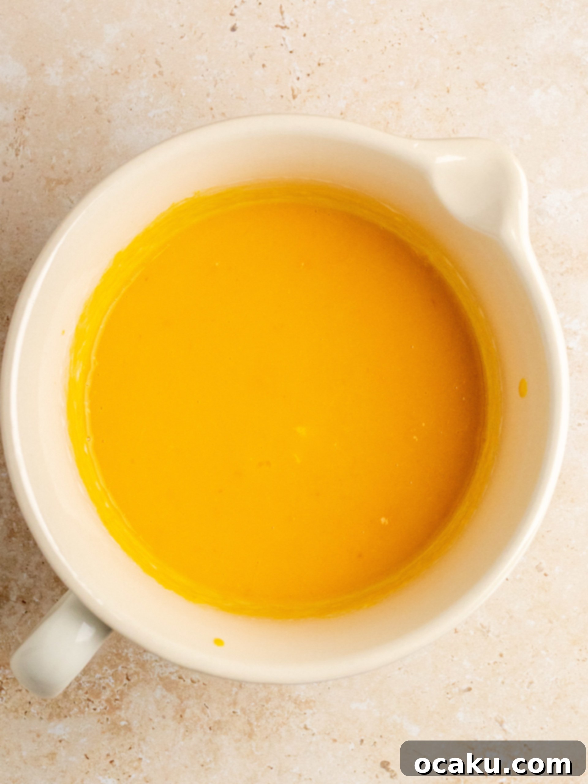 Mixing wet ingredients in a separate bowl for pumpkin chocolate chip bread.