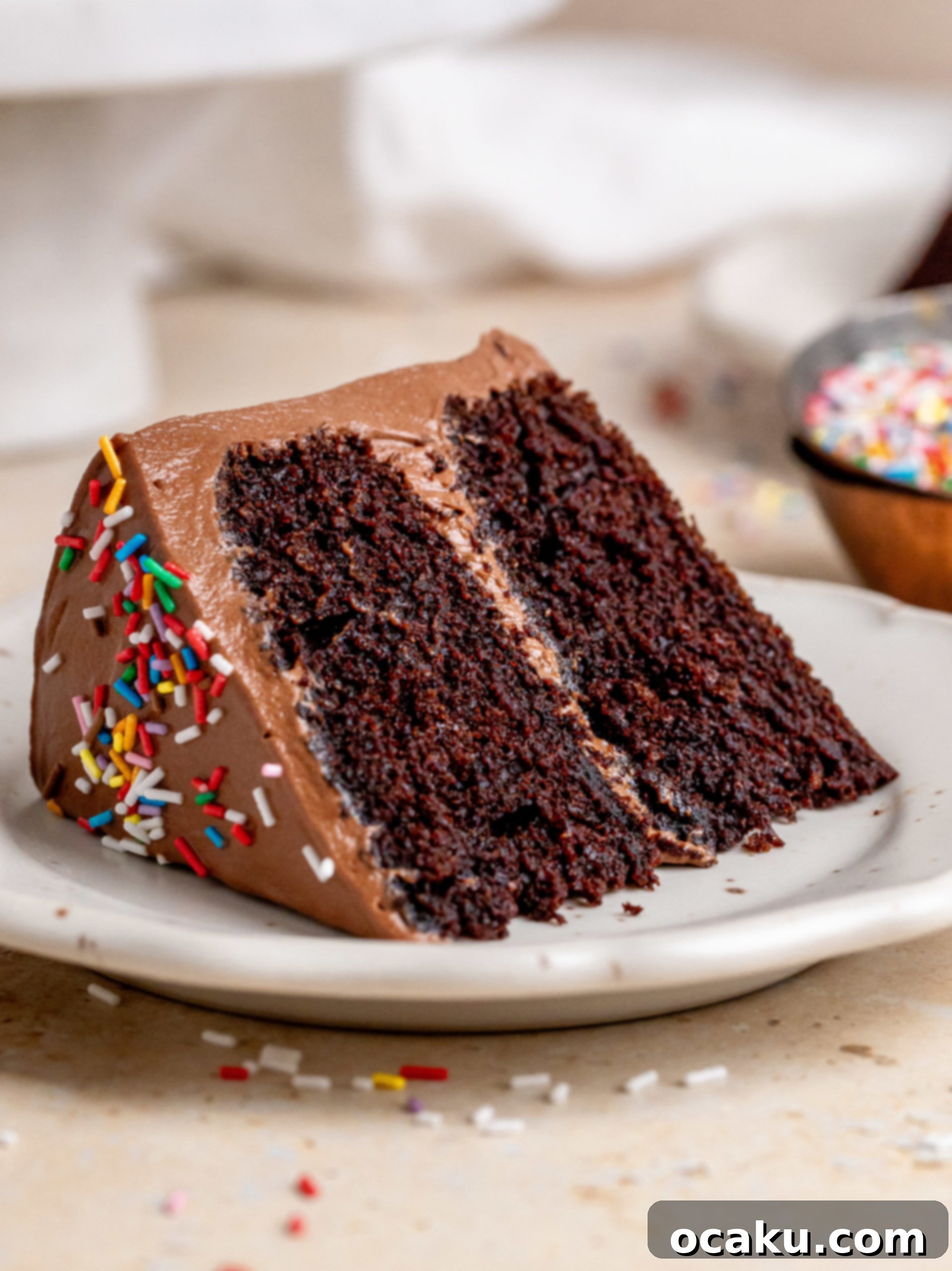 A slice of mini chocolate cake on a white plate, revealing the moist layers and rich buttercream, with a fork ready to dig in.