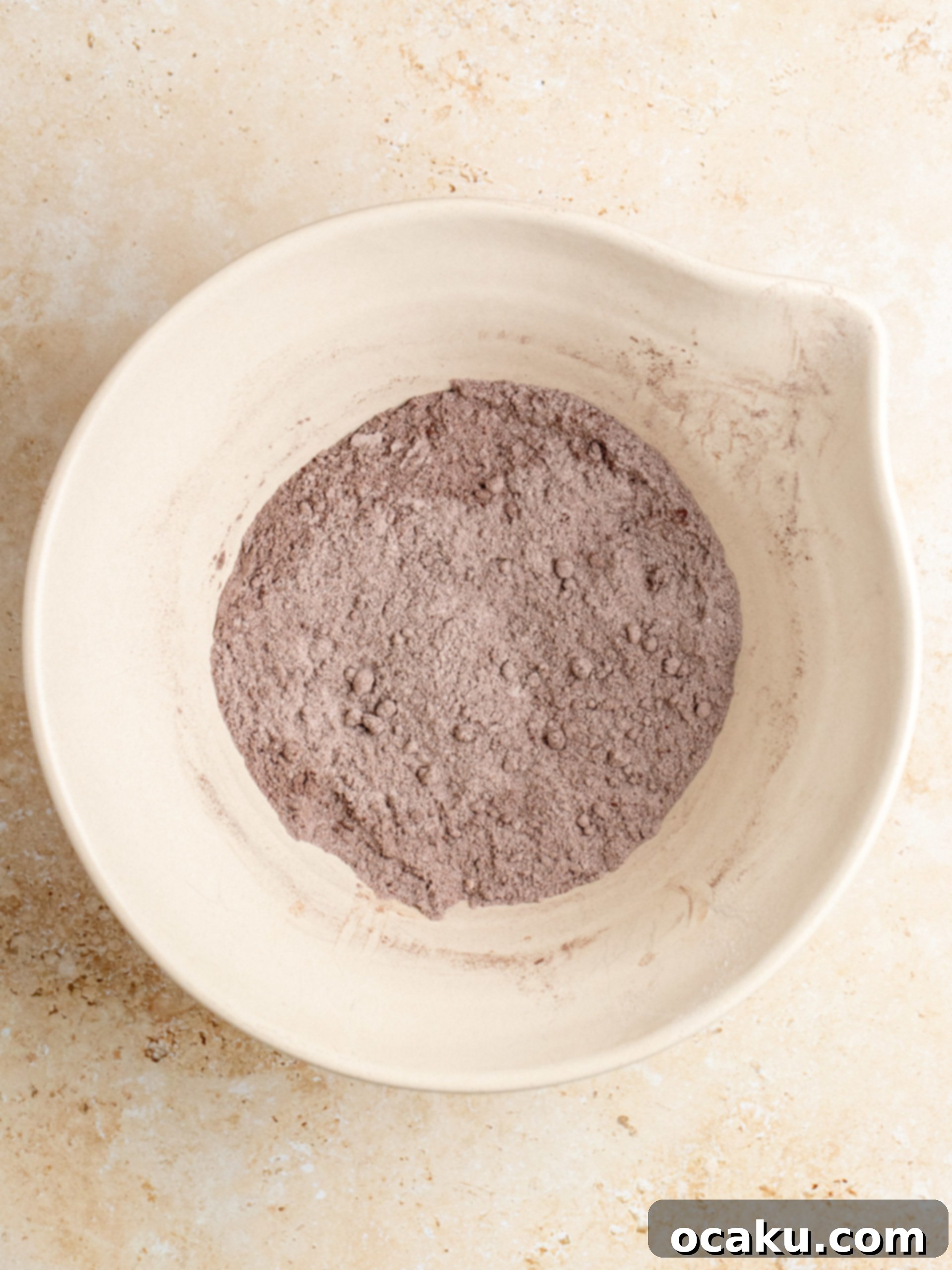 Dry ingredients for chocolate cake sifted into a bowl.