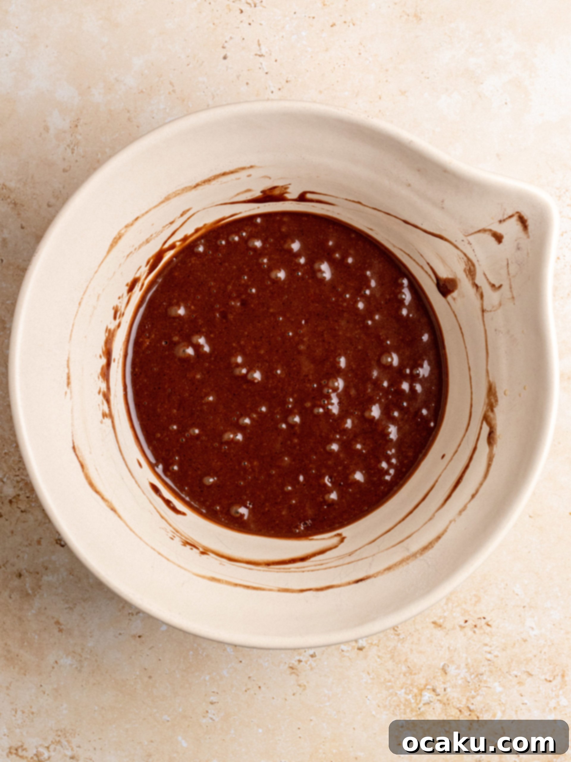 Wet ingredients being slowly poured into dry ingredients, ready for gentle mixing.