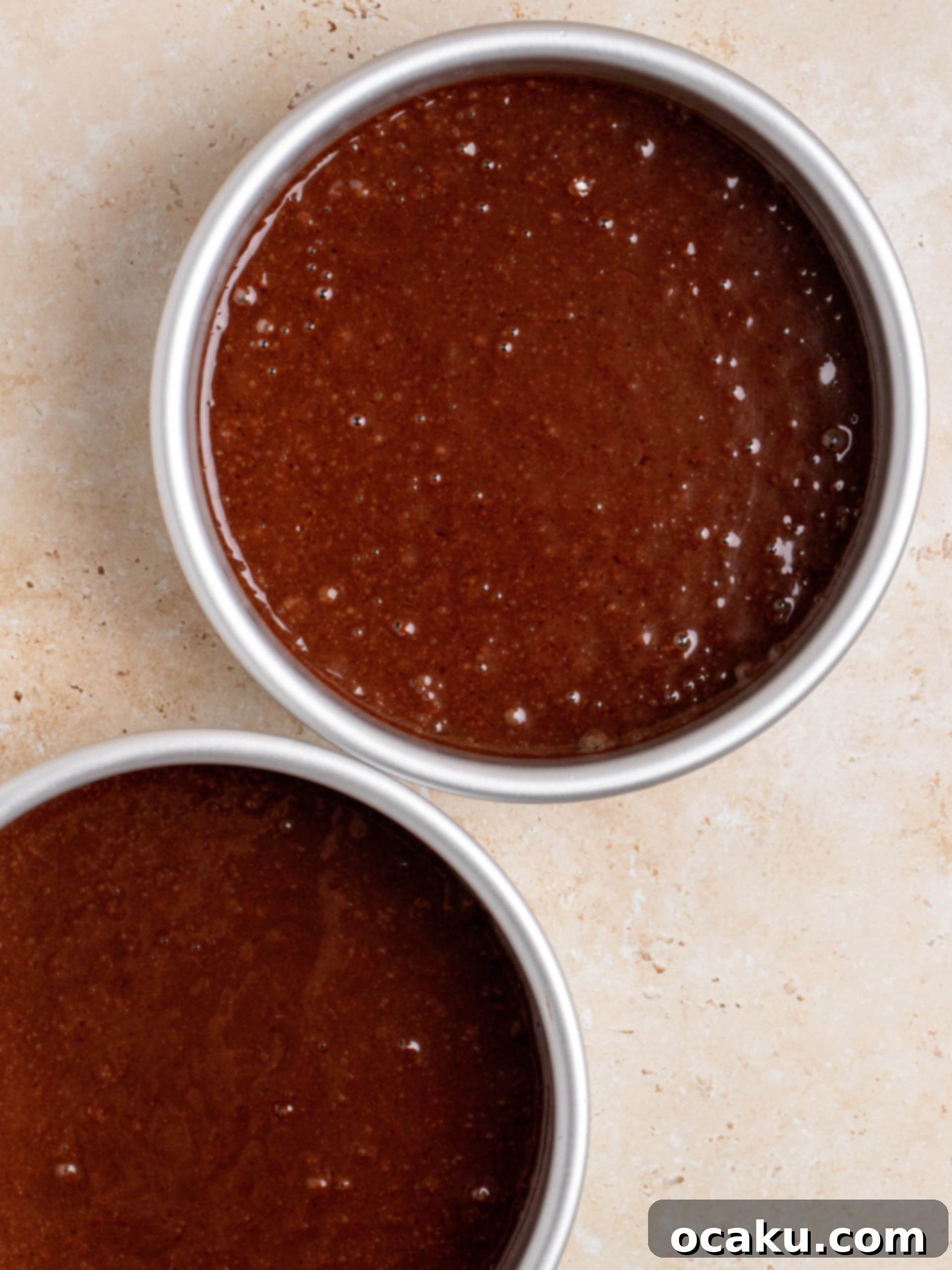 Chocolate cake batter divided evenly into two 6-inch prepared baking pans.