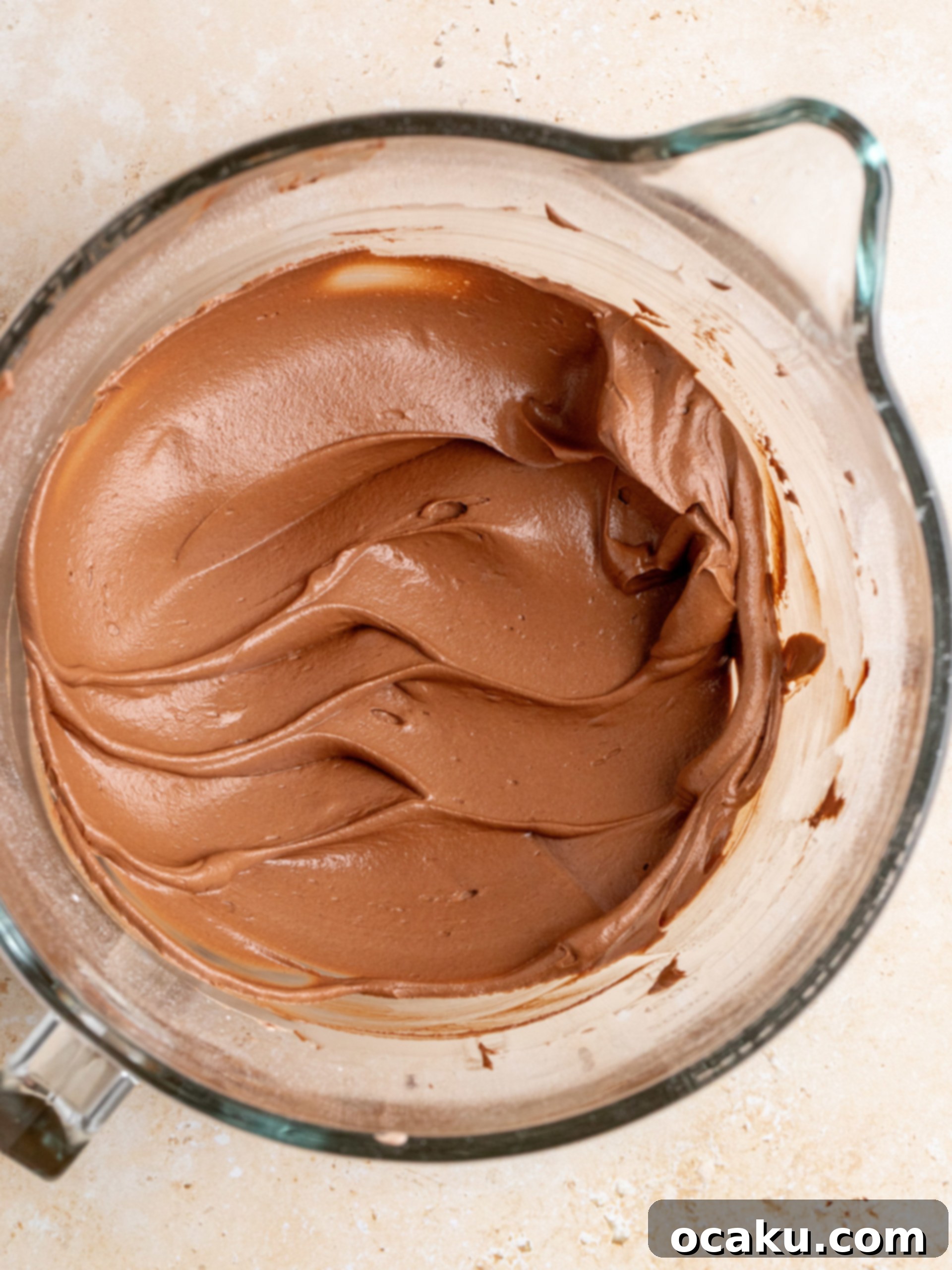 Assembled mini chocolate cake with buttercream spread between layers, ready for final frosting.
