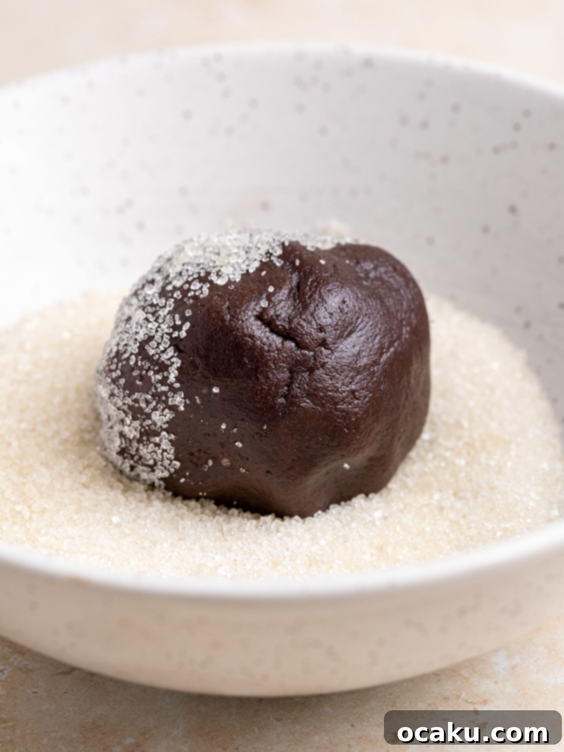A hand gently molding cookie dough around a frozen Nutella dollop, preparing it for baking.