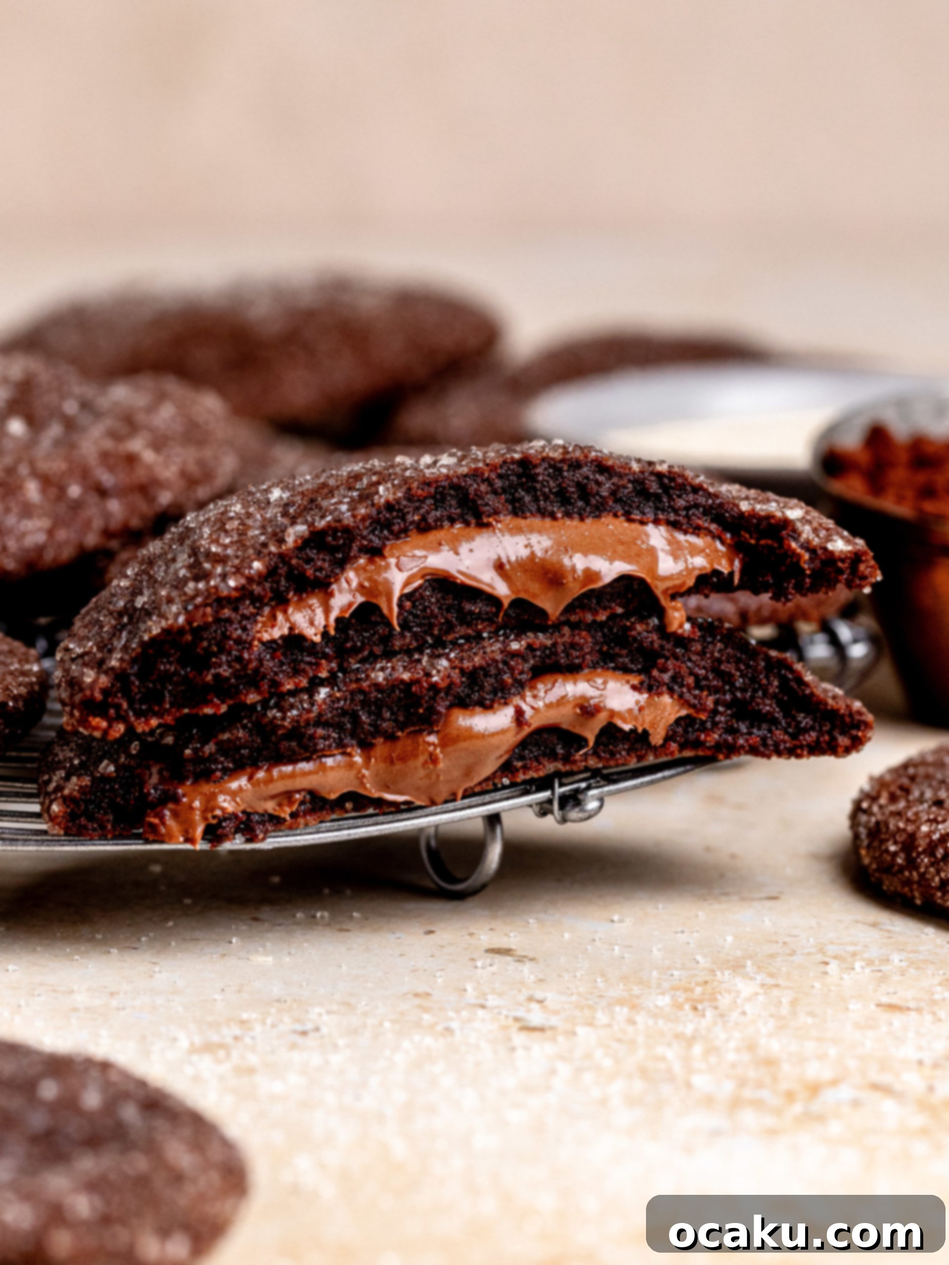 A plate of two freshly baked Nutella Stuffed Cookies, one with a bite taken out to show the melted Nutella filling.