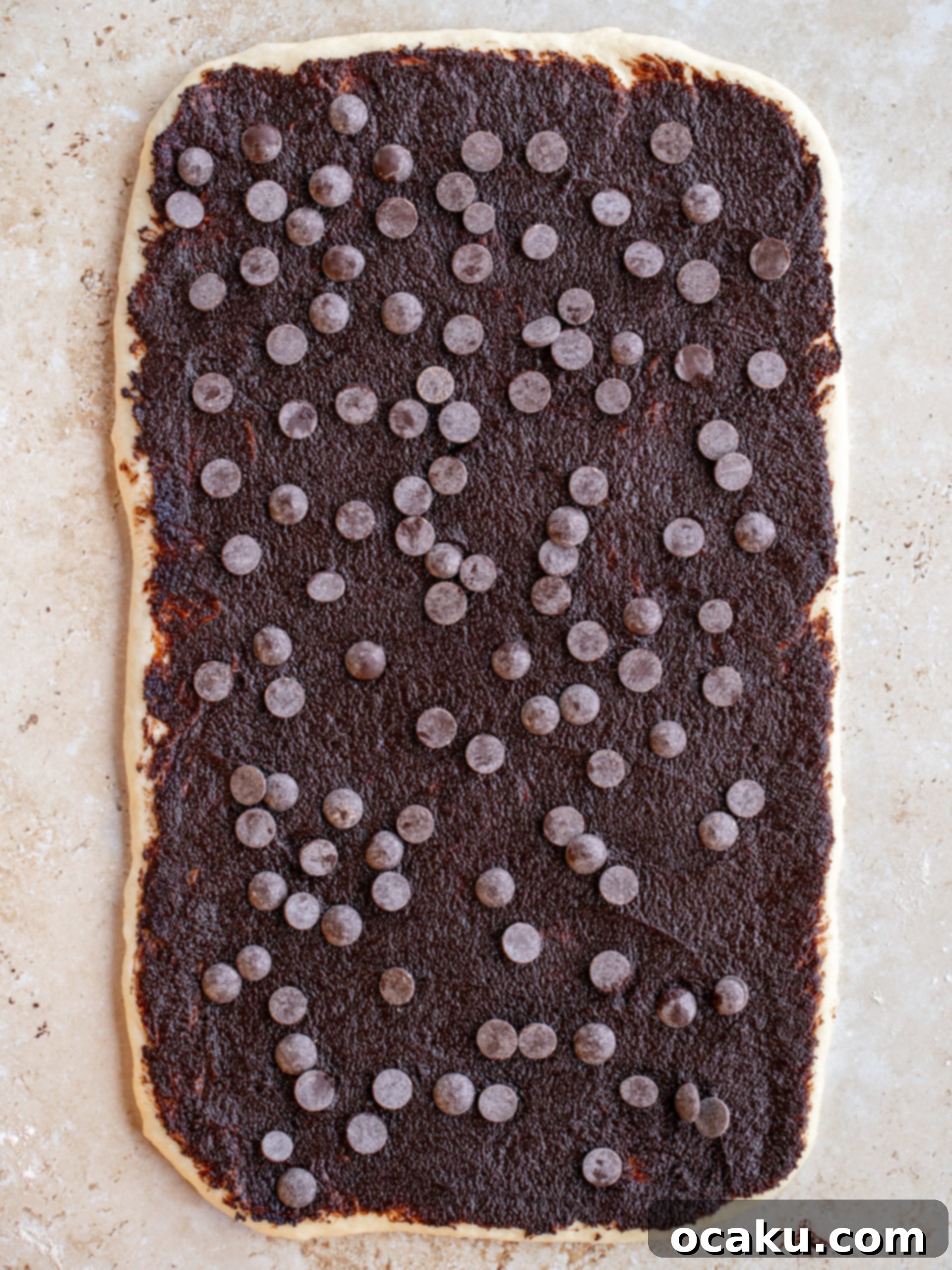 Chocolate cinnamon roll log being cut into individual rolls