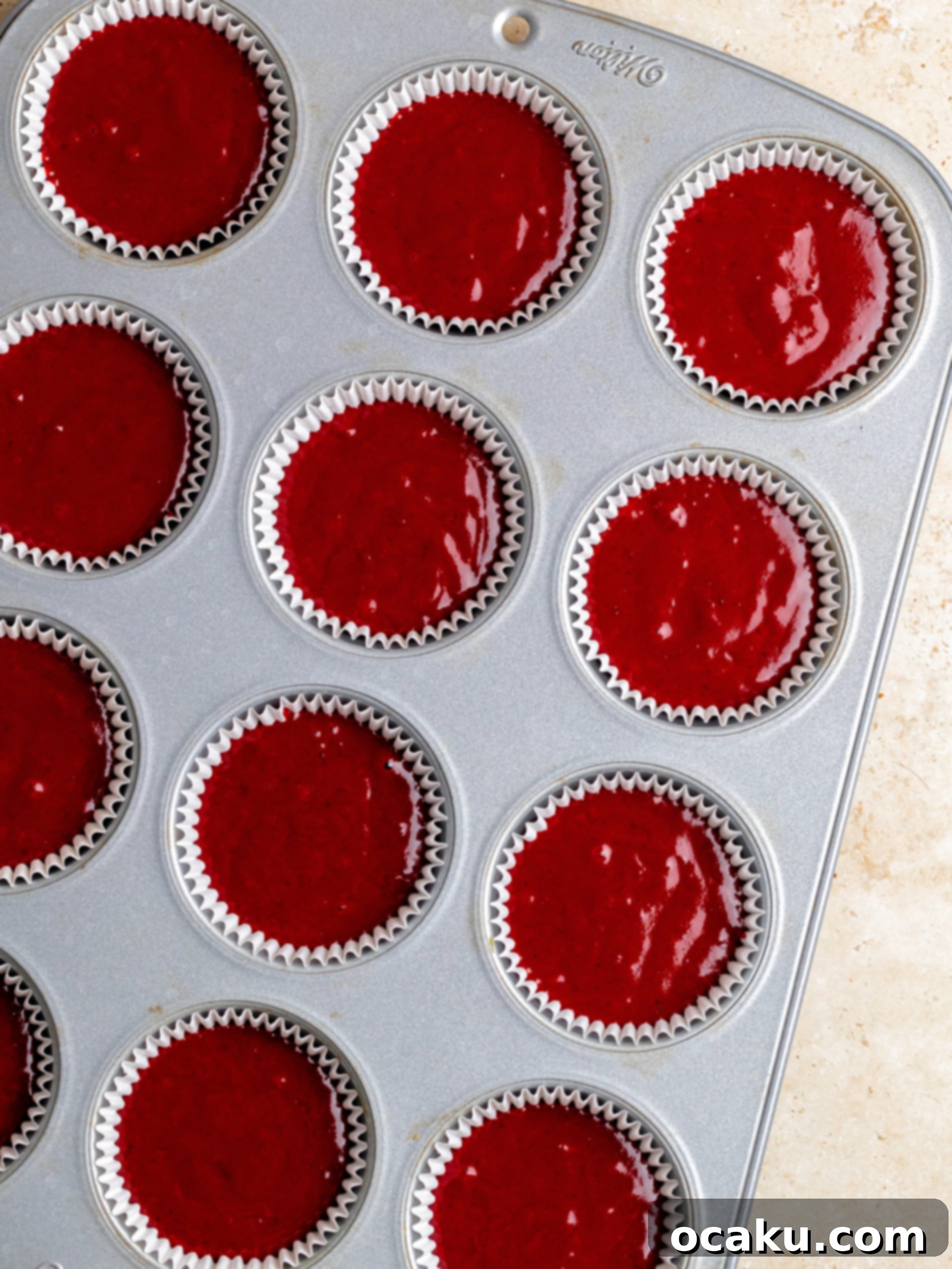 Red velvet cupcake batter poured into cupcake liners